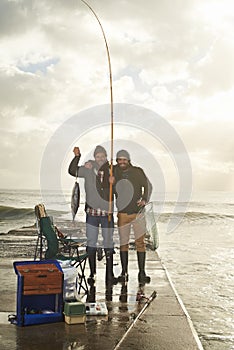 Happy, portrait and people at ocean fishing with pride to catch tuna on pier at sunset. Fisherman, friends and smile