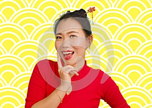 Happy portrait of young beautiful and sweet Asian Chinese woman in traditional bun hair style and red dress celebrating New Year