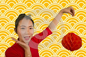 Happy portrait of young beautiful and sweet Asian Chinese woman in traditional bun hair style and red dress holding lantern