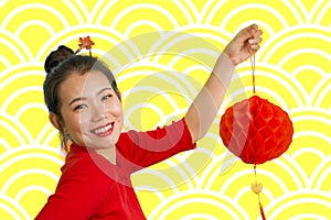 Happy portrait of young beautiful and sweet Asian Chinese woman in traditional bun hair style and red dress holding lantern