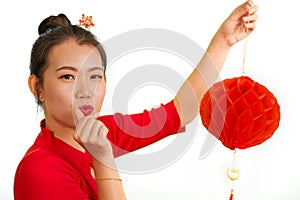 Happy portrait of young beautiful and sweet Asian Chinese woman in traditional bun hair style and red dress holding lantern doing