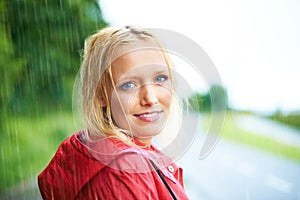 Happy, portrait and young woman in the rain with coat in nature, road or street for winter. Smile, positive attitude and