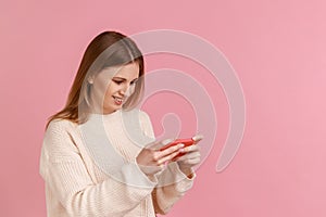 Happy positive blond woman holding smart phone, playing video games, successfully completing level.