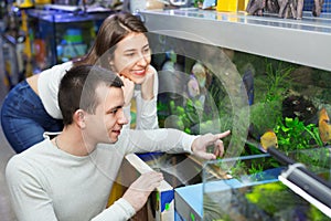 Happy positive customers selecting tropical fish in aquarium tan