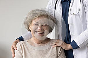 Happy positive elderly patient woman posing near geriatrician doctor