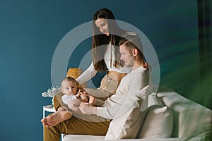 Happy positive family of the Caucasian race, a young father and mother, a little son are resting at home, sitting on a sofa