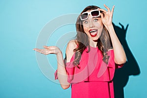 Happy positive girl in sunglasses holding copyspace on her palm