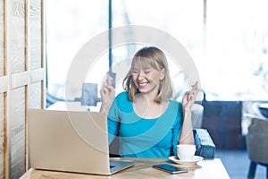 Happy positive hopeful woman working on laptop, crossing fingers, making wish, keeps eyes closed.