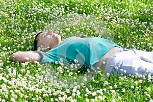 Happy positive man lying on a green summer meadow