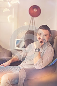 Happy positive man sitting in the armchair