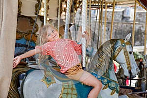 Happy positive preschool girl having a ride on the old vintage merry-go-round in city of St Malo France. Smiling child