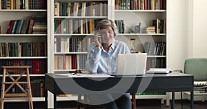 Happy positive senior 60s business woman talking on mobile phone