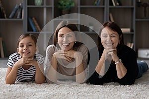 Happy positive three female generations family lying on carpet.