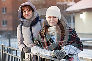 Happy positive two stylish girls standing on street in city. Closeup portrait funny joyful attractive young women dressing winter