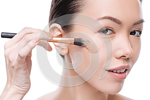 Happy positive woman applying foundation make up