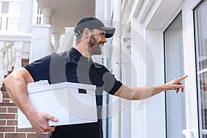 Happy postman with package waiting for customer photo