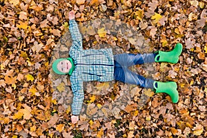Happy preeten boy lay at maple foliage