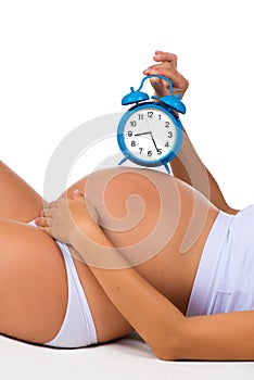 Happy pregnancy. Pregnant belly with alarm clock. Soon birth.