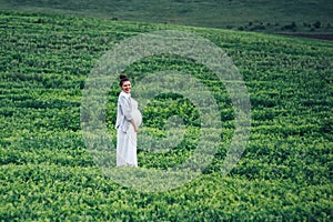 Pregnant women in green field in white dress