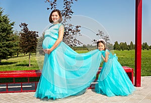 Happy pregnant asian mom and child girl hugging. The concept of childhood and family. Beautiful Mother and her baby outdoor