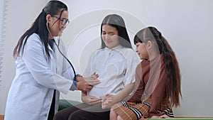 Happy pregnant asian woman appointment with doctor while daughter by side at hospital or clinic.