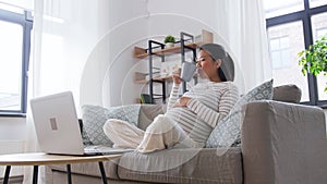 happy pregnant asian woman with laptop at home