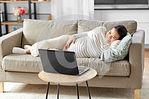 happy pregnant asian woman with laptop at home