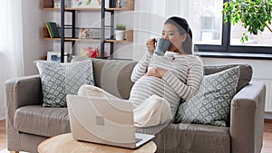 happy pregnant asian woman with laptop at home