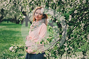 Happy pregnant blonde beautiful woman walking outdoor in spring park or garden