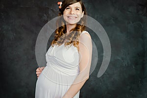 Happy pregnant caucasian young woman on dark backdrop. Maternity, femininity, mother`s day concept.