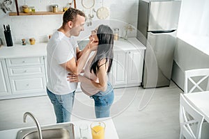 Happy pregnant couple hugging in kitchen with orange juice