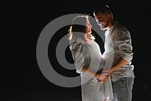 Happy Pregnant Couple. Mother and Father Love expecting Baby during Pregnancy. Family waiting Child Birth over Black