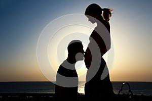 Happy pregnant couple silhouette on nature background coloring