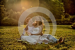 Happy pregnant couple sitting on the grass in park