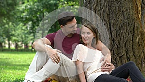 Happy pregnant couple sitting in park, planning secured family life, welfare