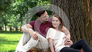 Happy pregnant couple sitting in park, planning secured family life, welfare