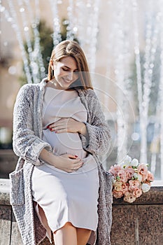 Happy pregnant girl near the fountain