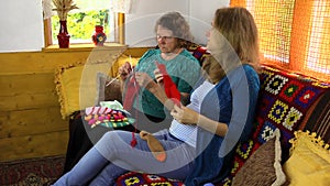 Happy pregnant granddaughter spend time knit with senior woman