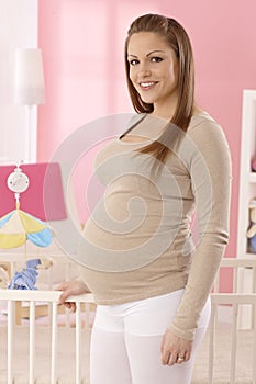 Happy pregnant mother in baby's room