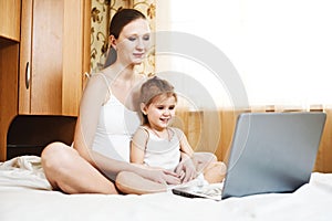 Happy pregnant mother and child with laptop