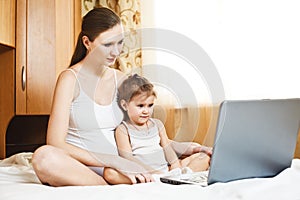 Happy pregnant mother and child with laptop