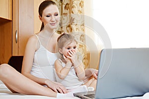 Happy pregnant mother and child with laptop comput