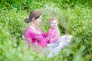 Happy pregnant mother playing with her baby daughter