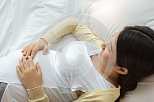 Happy pregnant mother touching beautiful belly laying down in cozy bed at home. prenatal, pregnancy, motherhood, expectation