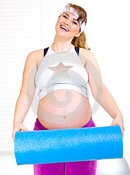 Happy pregnant woma with exercise mat