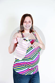 Happy pregnant woman with baby clothes