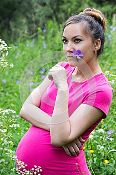 Happy pregnant woman with big belly and flower rest