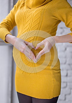 Happy pregnant woman with big belly showing love sign