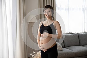 Happy pregnant woman in black underwear holding big baby bump