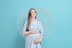 happy pregnant woman on blue background in blue home bathrobe